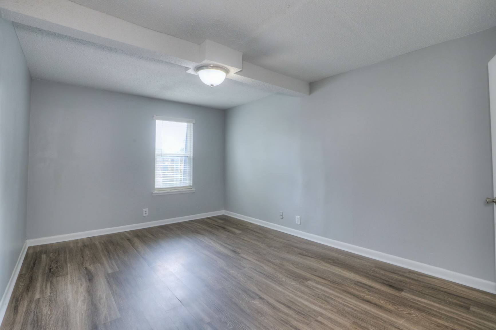 A room with a window and wooden flooring.